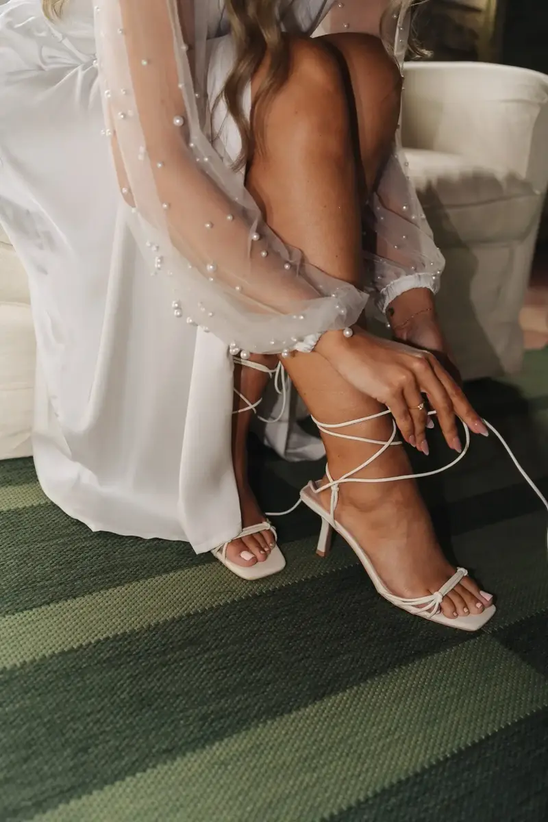 Braut schnürt beim Getting Ready ihre Sandalen